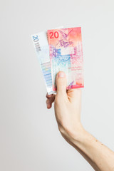 20 EUR and 20 CHF banknotes held in hand.
