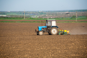 Obraz premium The farmer on the tractor with the attached mechanical seeder