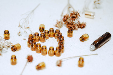 1ml amber glass vials arranged in love heart shape with dried flowers and roller bottles. Natural...