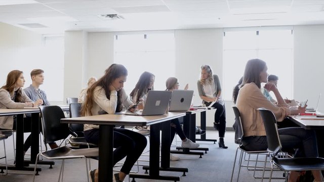 Female professor helping college students in classroom