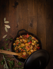 Vegan mixed stewed vegetables with spices and herbs in cast iron pot