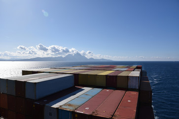 Containers loaded on the cargo ship sailing near sea coast.