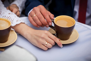 Two hands, male and female, with the wedding rings touch of brown coffee cup
