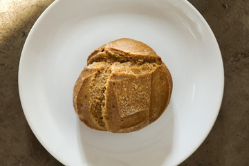 Soft fresh baked white bread with a crispy crust on a white plate on textured table