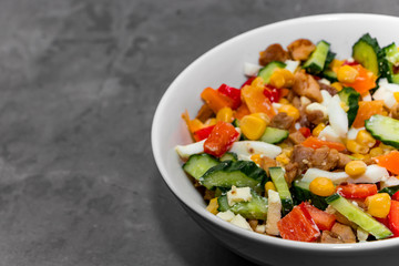 Bright vegetable salad with chicken on a gray concrete background. Making a delicious salad for a healthy diet.