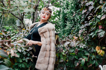 a gorgeous woman in a fur cape is surrounded by green ivy on her head a tiara, a bead hairstyle...