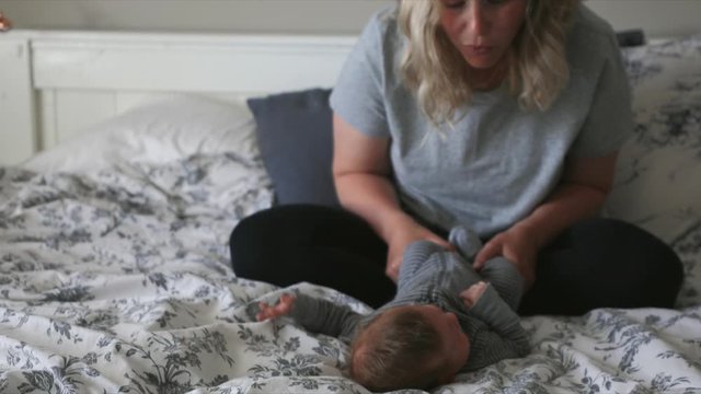 Playful mother and baby son on bed