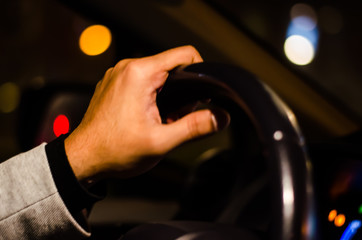 A man's hand driving a car in the night through the high way