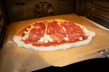homemade pizza dough with tomato sauce and mozzarella on baking paper