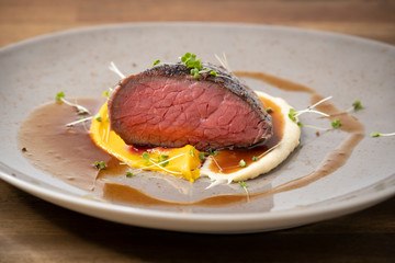 perfectly sous vide cooked medium beef steak, a piece cut, on two types of puree with dark sauce