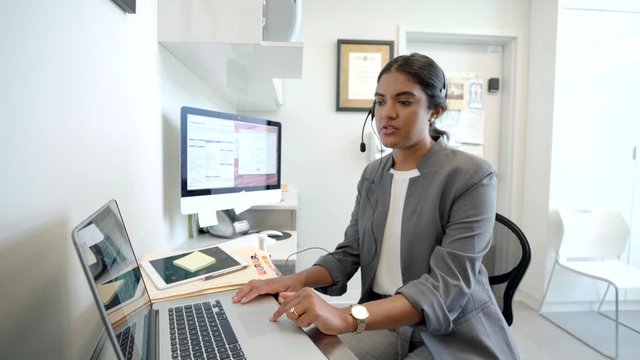 Female Doctor With Headset Talking On Telephone At Laptop In Clinic Doctors Office