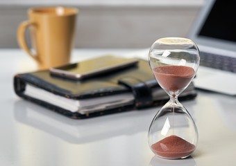 Hourglass on office desktop.