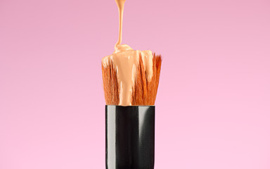 Makeup liquid foundation pouring on make-up Kabuki brush, contouring. closeup. Foundation beauty...