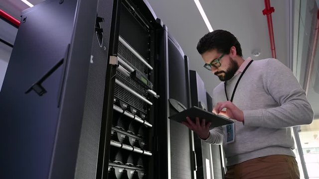 IT Technician With Digital Tablet Working In Server Room