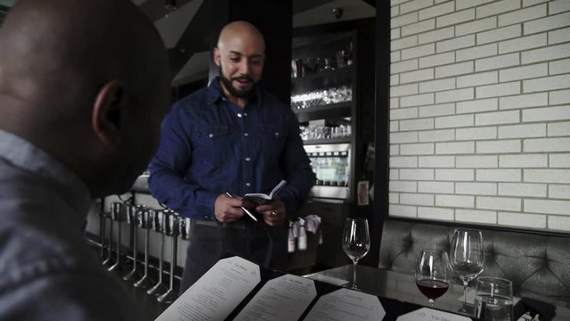 Waiter Taking Order From Man In Restaurant