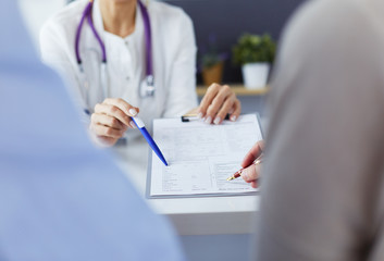 Doctor and patient examining a file with medical records, she is sitting on a wheelchair