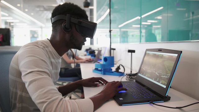 Student wearing VR headset and using laptop in classroom