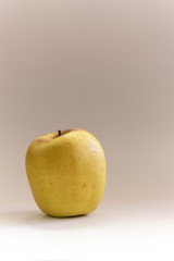 Vertical close up of a golden yellow apple