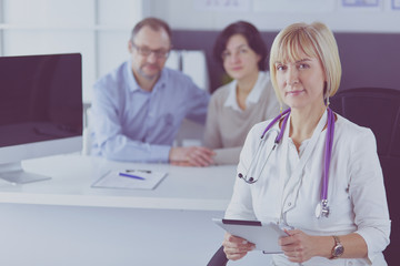 Fototapeta premium Dctor and patient sitting at the desk. Physician pointing into tablet pc