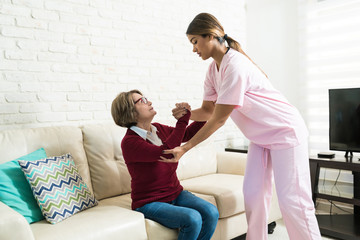 Caregiver Supporting Senior Female To Sit