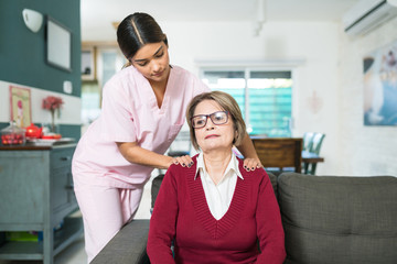 Caregiver Taking Care Of Elderly Patient At Home