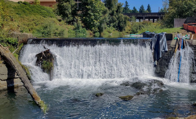 Thundering Upper Tumwater Falls pouring into the creek with a log and a bridge construction...