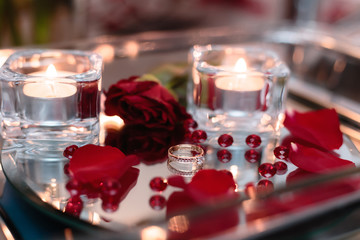 Wedding ring in rose petals against the background of candles