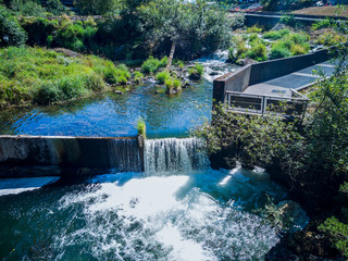 Scenic Upper Tumwater Falls cascading into a creek with a dam and a walkway trees grass in a...
