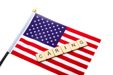 The flag of the United States isolated on a white background with a sign reading Caring