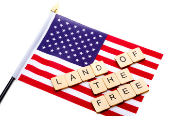 The flag of the United States isolated on a white background with a sign reading Land of The Free