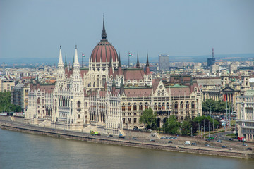 Fototapeta na wymiar Hungarian Parliament (Országház) and other buildings of the city next to Danube river. Landscape view in the morning. Budapest, Hungary.