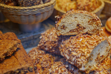 Selected focus view of cutting heap and stack of ROSINENSTRIEZEL,  Raisins fruit breads, with another type of breads at display of bakery store. 