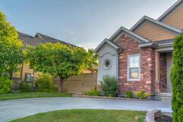 Landscaped front yard of a home with grasses trees and driveway against sky