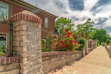 Pathway along stone and wire fence of ressidential building with red brick wall