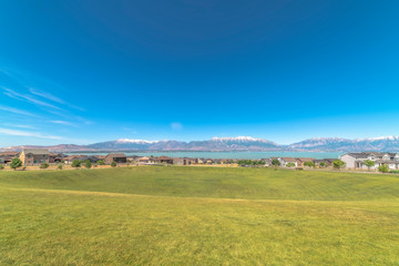 Obraz premium Golf course blanketed with vibrant green grasses overlooking homes and lake