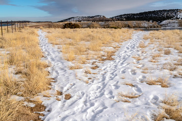 Hiking trails covered with snow overlooking scenic hills and lake in winter