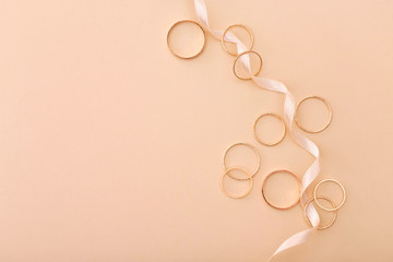 Many golden rings and ribbon on beige background