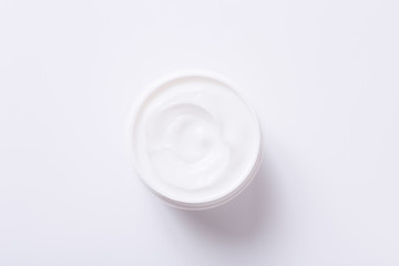 Open white container with cosmetic cream on white background. Cosmetic moisturizing product.