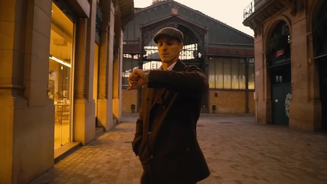 Old Fashion Man from the 1920s england in historical part of city. He is checking time on his wrist watch