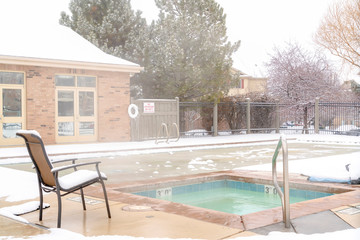Frozen swimming pool area surrounded by snow on a foggy and cold winter day