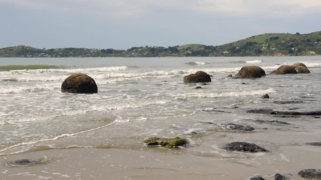 Moeraki boulders in the surf on Koekohe Beach on the Otago coast, New Zealand. 