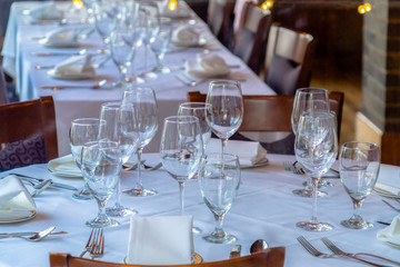 Wine glasses spoons forks saucer plates and napkins on a table with white cloth