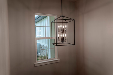 Geometric chandelier hanging from the ceiling of home against window and wall