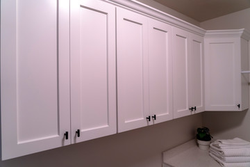 Interior wall of home lined with hanging wooden cabinets over a countertop