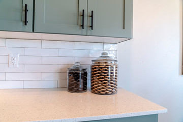 Jars of cookies on kitchen counter top against tile backsplash and white wall