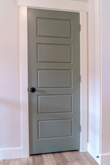 Gray door with matte black door knob and white door frame against wall