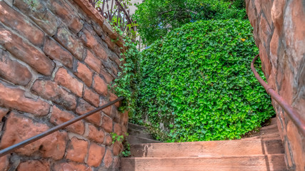 Panorama Close up of outdoor stairs amid stone brick retaining walls that leads to a home