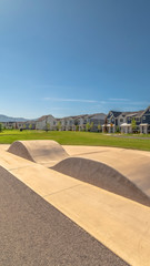 Obraz premium Vertical frame Ramp along a road and lawn in front of beautiful houses in the sunny suburbs