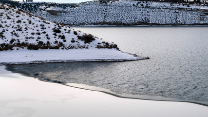 Panorama Sunny winter day views with cold calm lake and hills blanketed with white snow