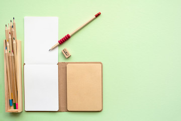 Environmentally friendly  Eco concept of notepad, pencils, sharpener on green background, top view, copy space